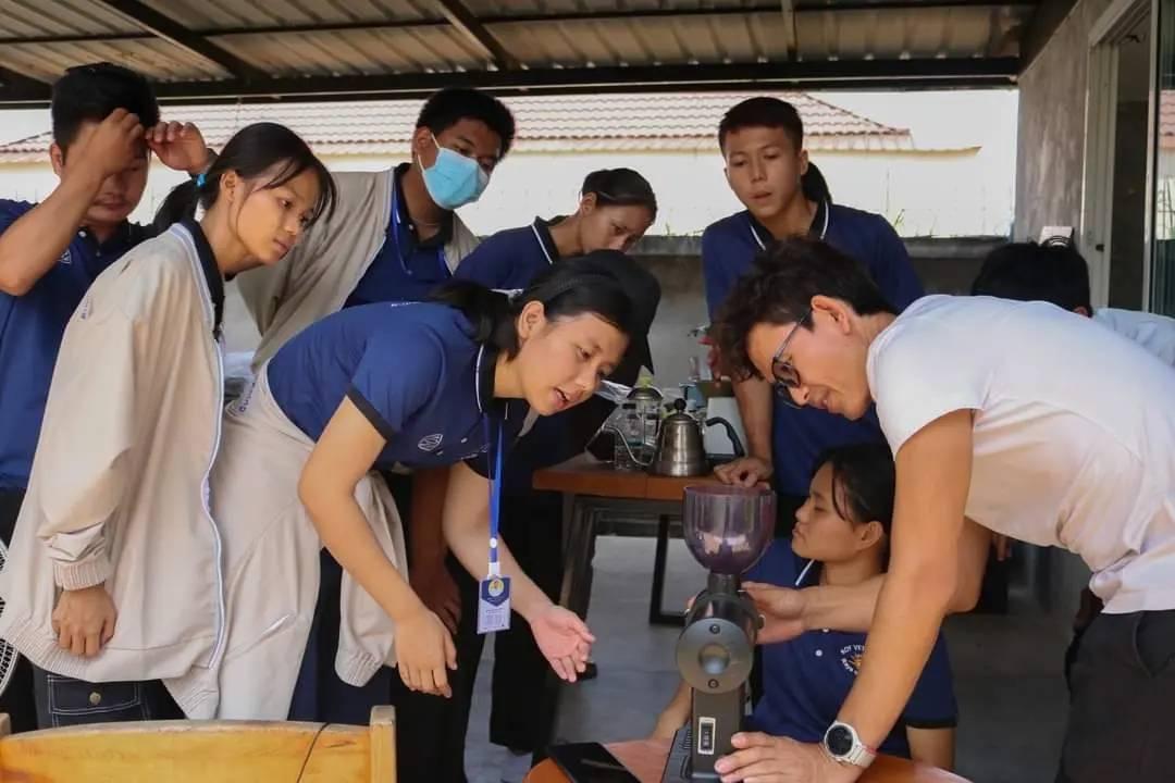 コーヒーミルの使い方を教わる移民学校の生徒たち